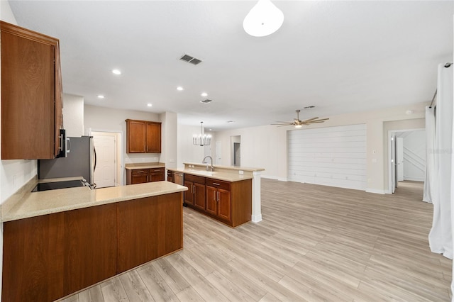 kitchen with sink, pendant lighting, kitchen peninsula, and light wood-type flooring