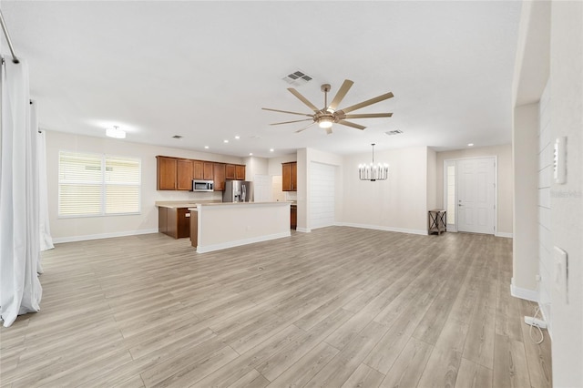 unfurnished living room with light wood-type flooring and ceiling fan with notable chandelier