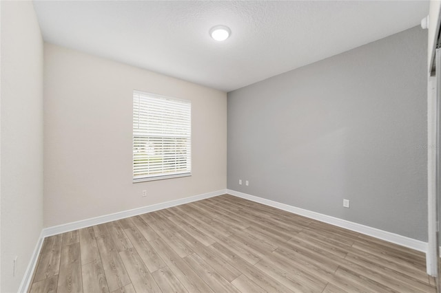 spare room featuring a textured ceiling and light hardwood / wood-style floors