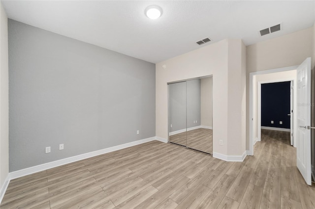 unfurnished bedroom with light wood-type flooring and a closet