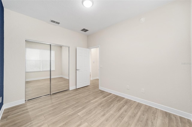 unfurnished bedroom with light wood-type flooring and a closet