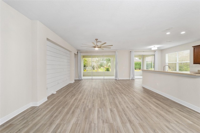 unfurnished living room with ceiling fan and light hardwood / wood-style flooring