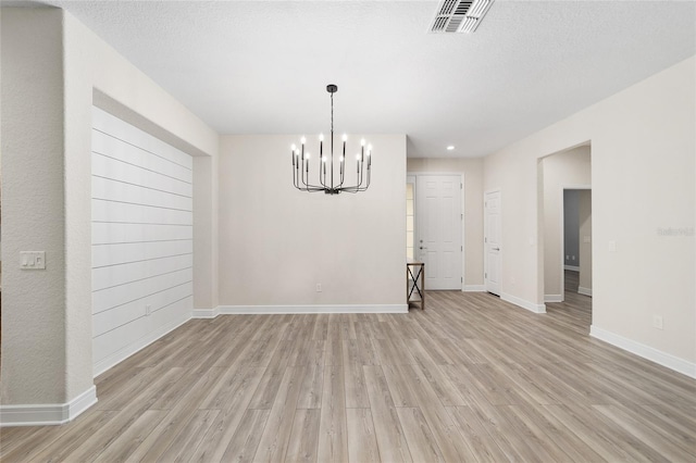 interior space featuring a textured ceiling, a chandelier, and light wood-type flooring