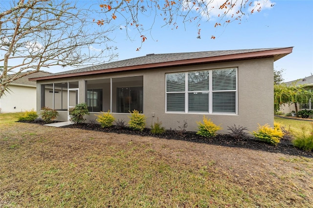 rear view of house with a sunroom and a lawn