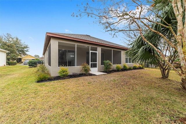 rear view of house featuring a lawn and a sunroom