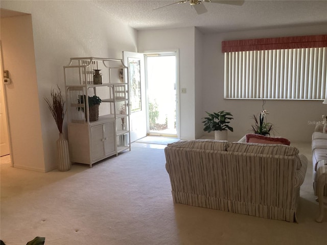 carpeted living room featuring ceiling fan and a textured ceiling