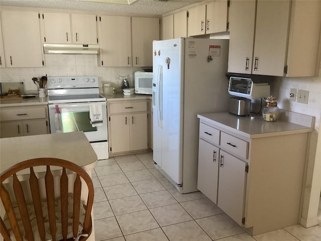 kitchen featuring light tile patterned floors, decorative backsplash, cream cabinets, and white appliances