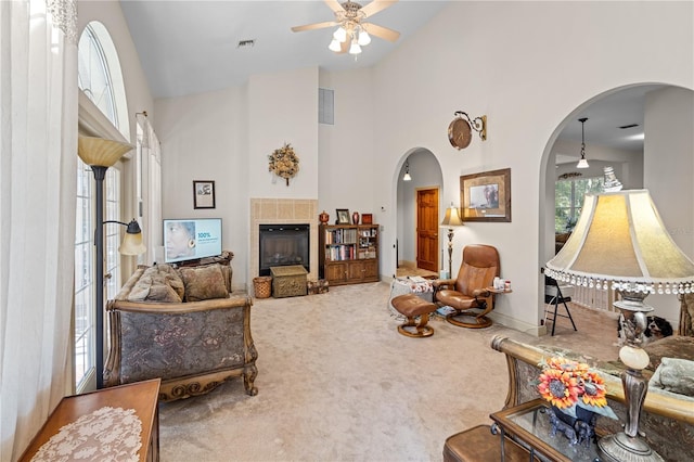 carpeted living room with high vaulted ceiling, a tile fireplace, and ceiling fan