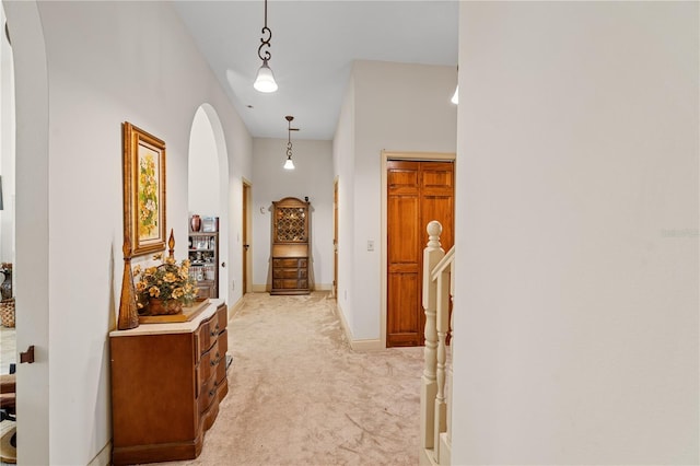 hallway featuring a high ceiling and light carpet