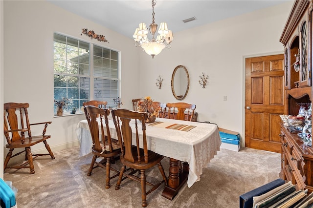 dining space featuring light carpet and a chandelier