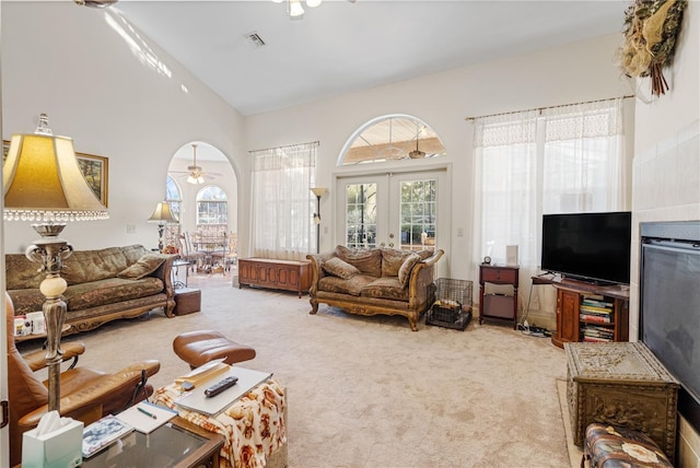 living room with a high ceiling, french doors, ceiling fan, and carpet