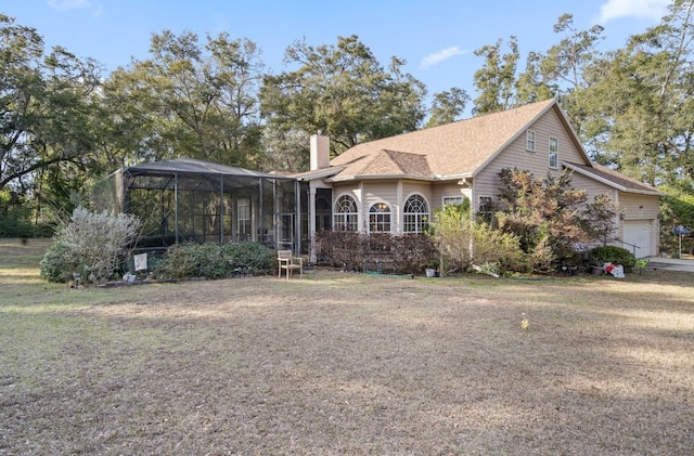 view of front of property featuring a garage, glass enclosure, and a front lawn