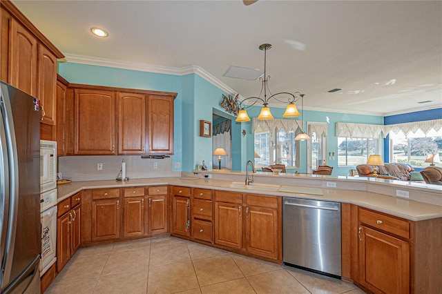 kitchen featuring appliances with stainless steel finishes, sink, hanging light fixtures, ornamental molding, and kitchen peninsula