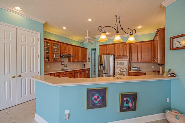 kitchen with crown molding, decorative light fixtures, light tile patterned floors, kitchen peninsula, and stainless steel appliances