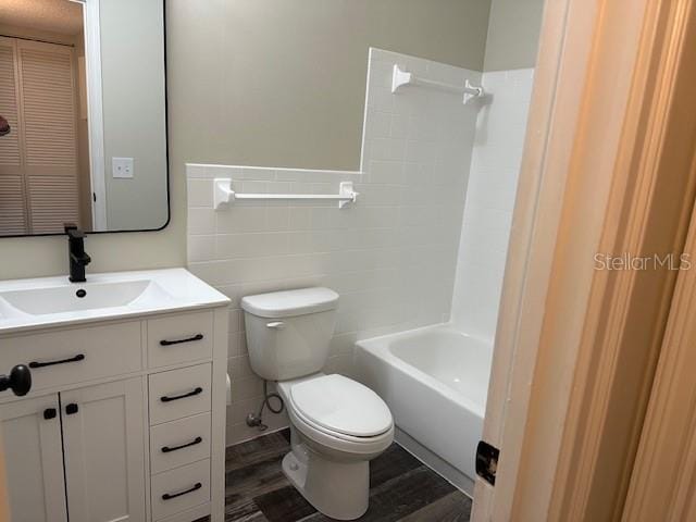 full bathroom with toilet, vanity, tile walls, shower / washtub combination, and hardwood / wood-style flooring