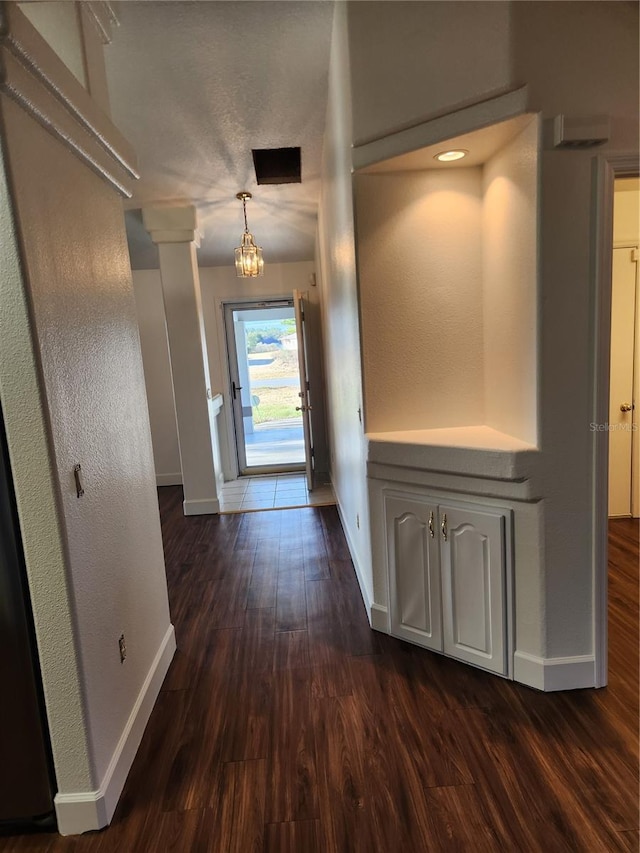 corridor with an inviting chandelier and dark hardwood / wood-style floors