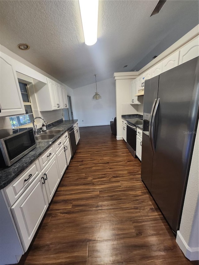 kitchen with appliances with stainless steel finishes, white cabinets, sink, hanging light fixtures, and dark hardwood / wood-style floors