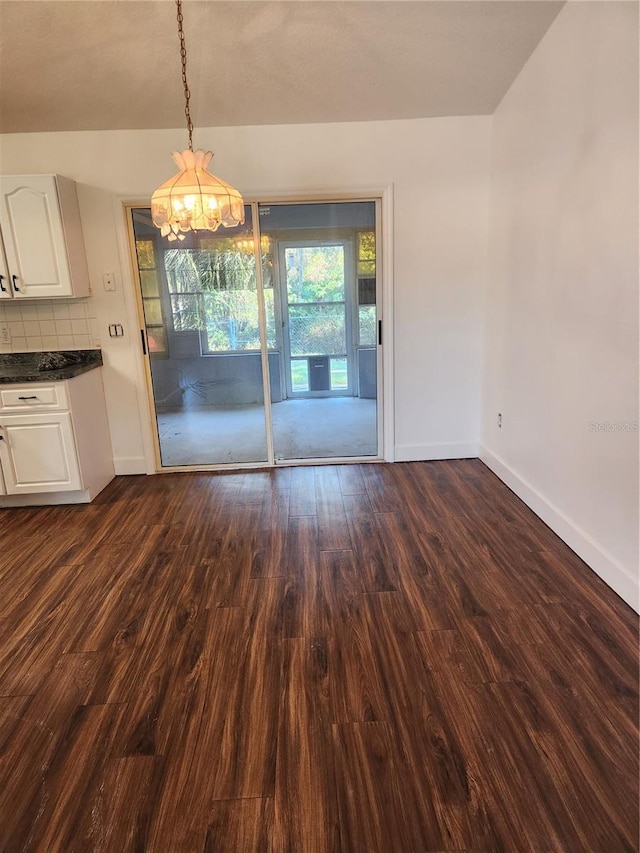 unfurnished dining area with dark hardwood / wood-style flooring and a chandelier