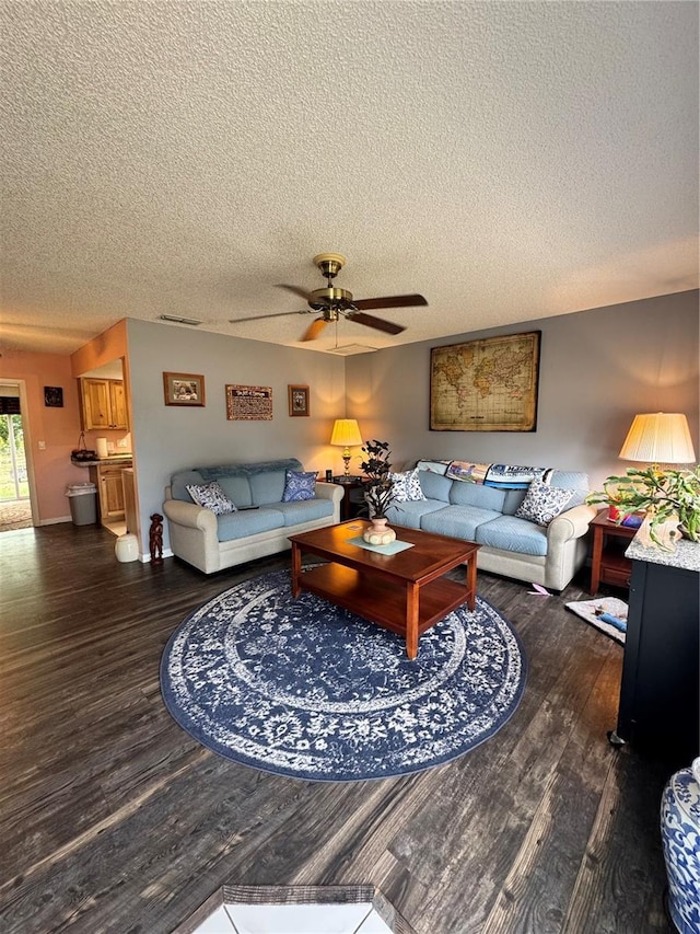 living room with ceiling fan, a textured ceiling, and dark hardwood / wood-style floors