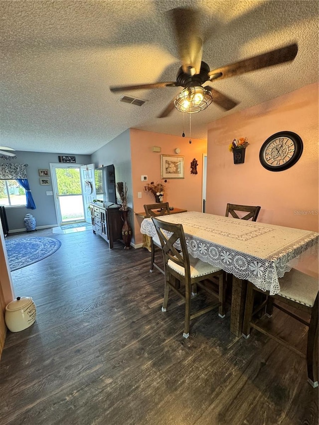 dining space featuring ceiling fan, dark wood-type flooring, and a textured ceiling