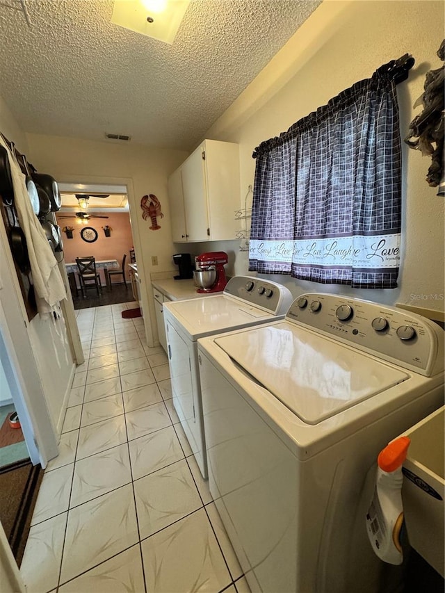 clothes washing area with light tile patterned flooring, separate washer and dryer, a textured ceiling, and cabinets