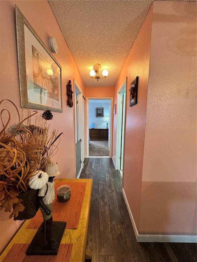 corridor with dark hardwood / wood-style floors and a textured ceiling