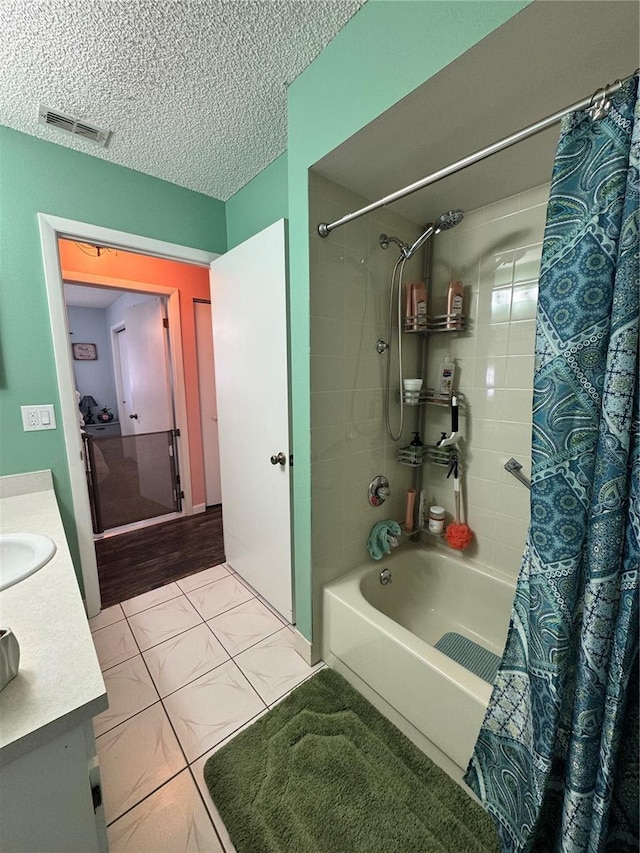 bathroom featuring a textured ceiling, tile patterned flooring, shower / bath combo, and vanity