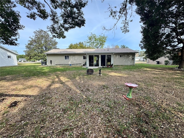 back of property featuring an outdoor fire pit and a yard