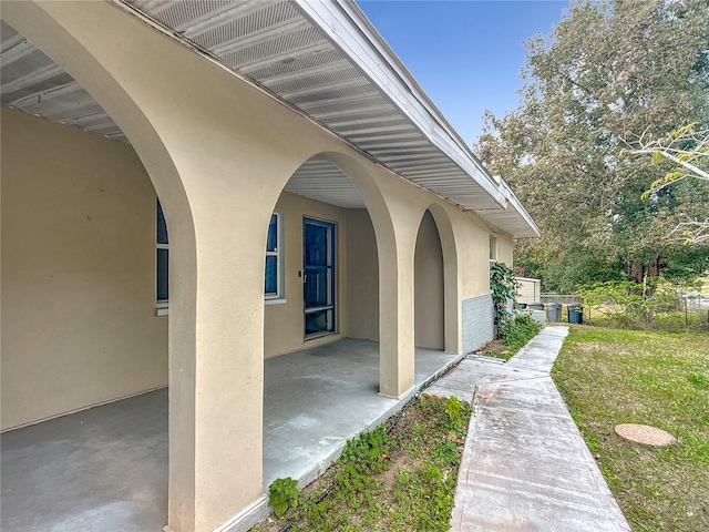 entrance to property featuring a patio area and a lawn