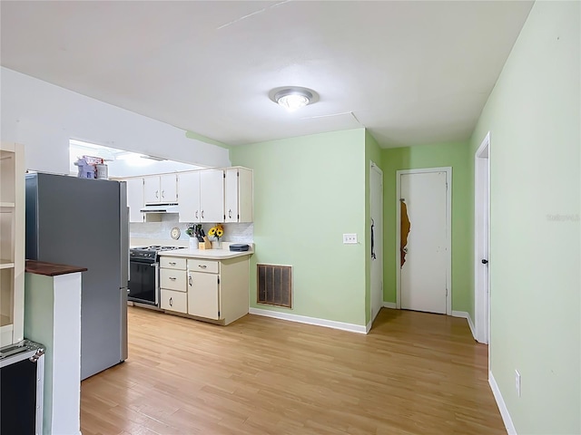 kitchen featuring electric stove, light hardwood / wood-style floors, decorative backsplash, white cabinetry, and stainless steel fridge