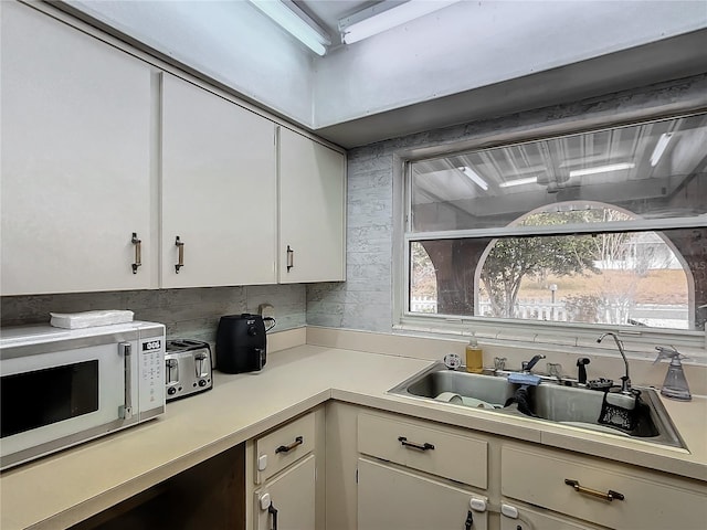 kitchen with sink, white cabinetry, and backsplash