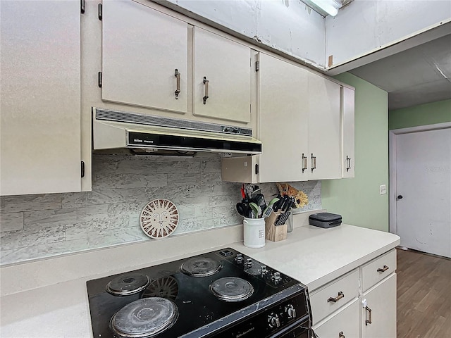 kitchen featuring hardwood / wood-style flooring, white cabinets, backsplash, and black / electric stove