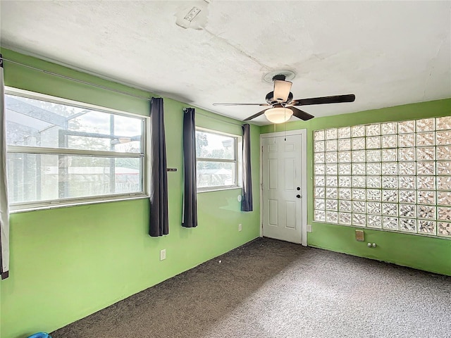 empty room featuring a textured ceiling, ceiling fan, plenty of natural light, and carpet floors