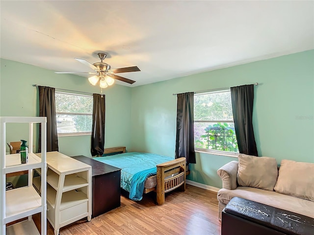 bedroom with ceiling fan, multiple windows, and light hardwood / wood-style flooring