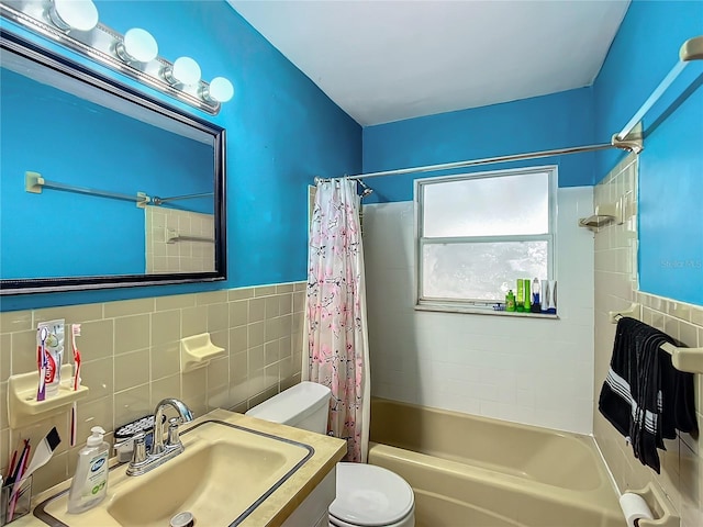 full bathroom featuring toilet, tile walls, sink, and shower / bath combo with shower curtain