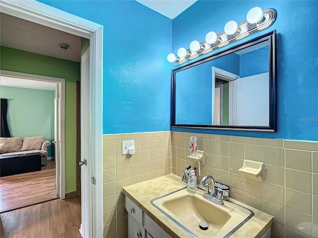 bathroom featuring wood-type flooring, vanity, and tile walls