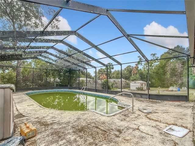 view of swimming pool featuring glass enclosure, a patio area, and a storage unit