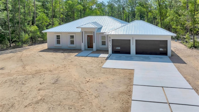6877 SW 131st Cir, Ocala, FL 34481 - view of front facade with concrete driveway, an attached garage, stucco siding, metal roof, and a view of trees