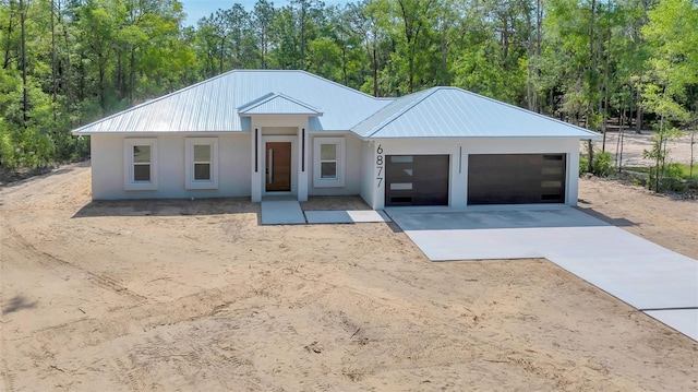 6877 SW 131st Cir, Ocala, FL 34481 - view of front of home with driveway, a garage, stucco siding, and metal roof