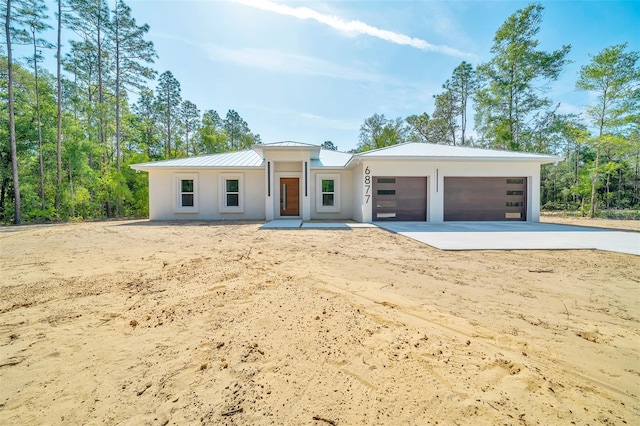 6877 SW 131st Cir, Ocala, FL 34481 - view of front facade featuring a standing seam roof, driveway, a garage, metal roof, and stucco siding