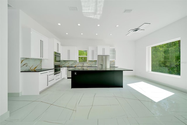 6877 SW 131st Cir, Ocala, FL 34481 - kitchen with dark countertops, stainless steel appliances, tasteful backsplash, a center island, and a sink