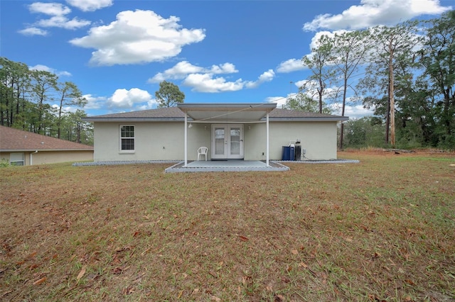 rear view of house featuring a patio, a lawn, and french doors