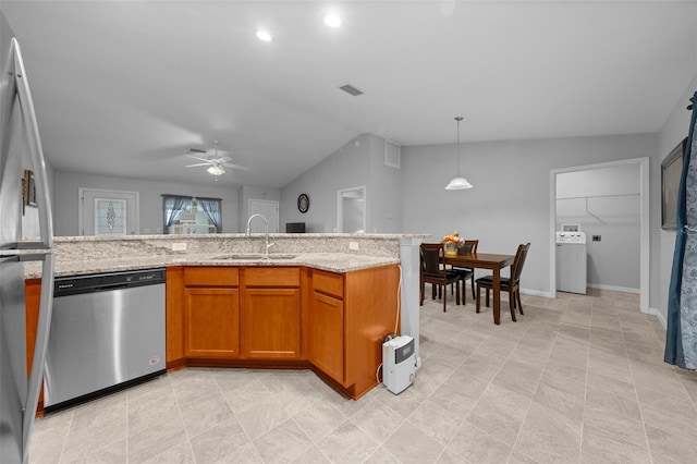 kitchen featuring lofted ceiling, sink, hanging light fixtures, stainless steel appliances, and light stone countertops