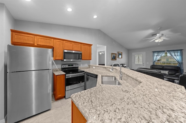 kitchen with sink, ceiling fan, appliances with stainless steel finishes, light stone countertops, and vaulted ceiling