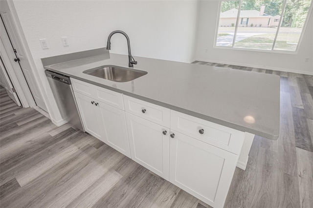 kitchen featuring light wood-type flooring, stainless steel dishwasher, white cabinets, and sink