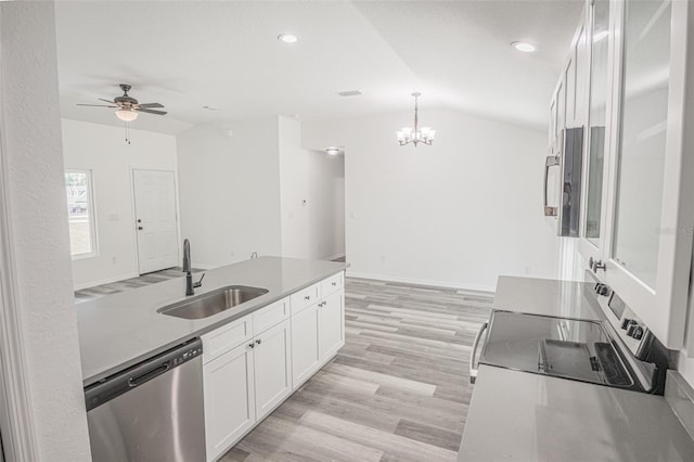 kitchen featuring lofted ceiling, pendant lighting, sink, stainless steel appliances, and white cabinets