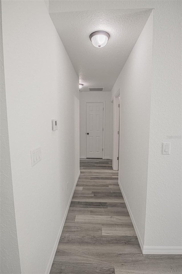 hall with a textured ceiling and dark wood-type flooring