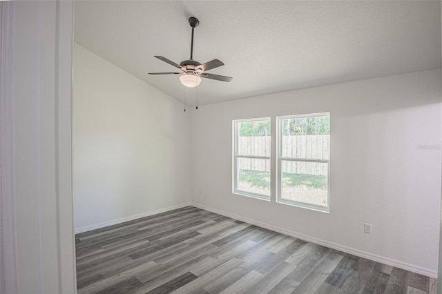 spare room featuring ceiling fan, vaulted ceiling, a textured ceiling, and wood-type flooring