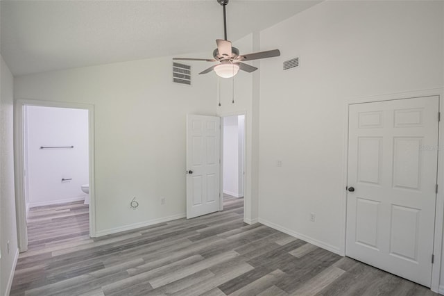 unfurnished bedroom featuring ceiling fan, ensuite bathroom, light hardwood / wood-style flooring, and high vaulted ceiling