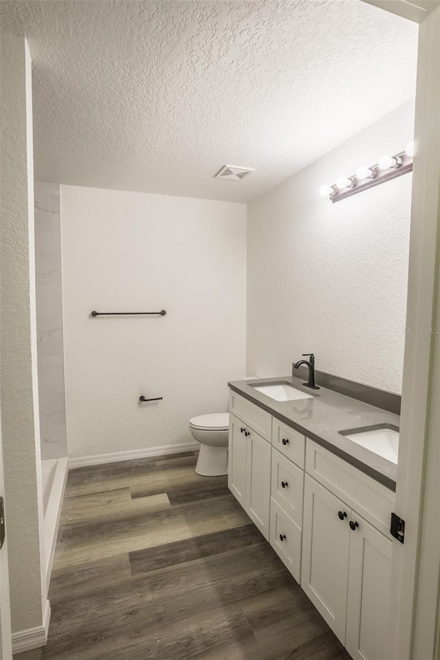 bathroom with toilet, a textured ceiling, hardwood / wood-style flooring, and vanity